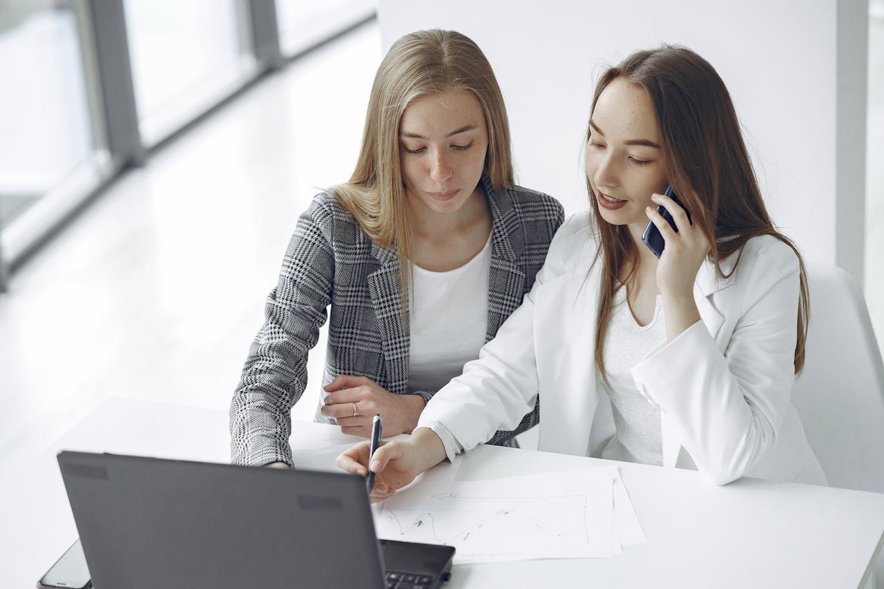 about-02 Two businesswomen collaborating at a desk with a laptop and documents.